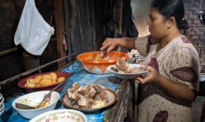 Foto : Mbah Rum pemilik warung makan lontong balungan legend saat menyajikan makanan (Sumber : Mitrapost.com/ Anang SY)