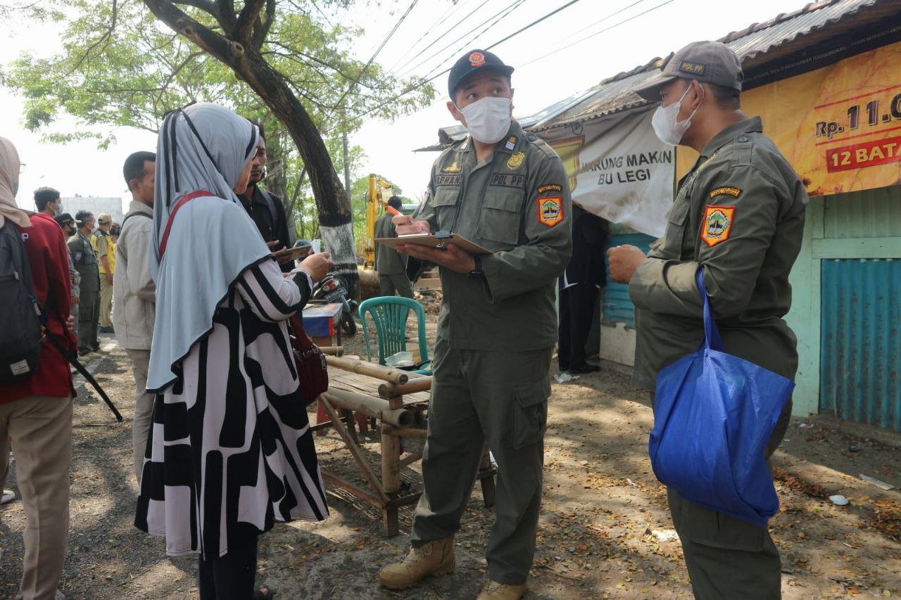 Foto : Bu Legi dan salah satu anggota Satpol-PP berkomunikasi mengenai pembongkaran warung (Sumber : mitrapost.com)