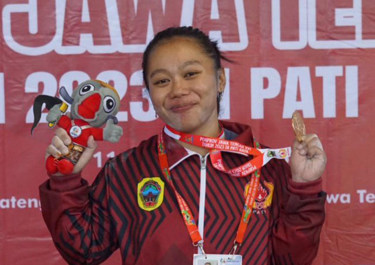 Foto : Laila Rahmawati sambil gendong sang anak terima medali emas dari cabor Angkat Berat Kelas 63 Kg Putri di ajang PORPROV XVI Tahun 2023 (Sumber : mitrapost.com/ Anang SY)