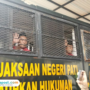 Foto : Supriyono alias Botok melambaikan tangan di dalam truk tahanan Kejaksaan Negeri Pati, Rabu (24/12/2025). (Sumber. Mitrapost.com/ Ilham)