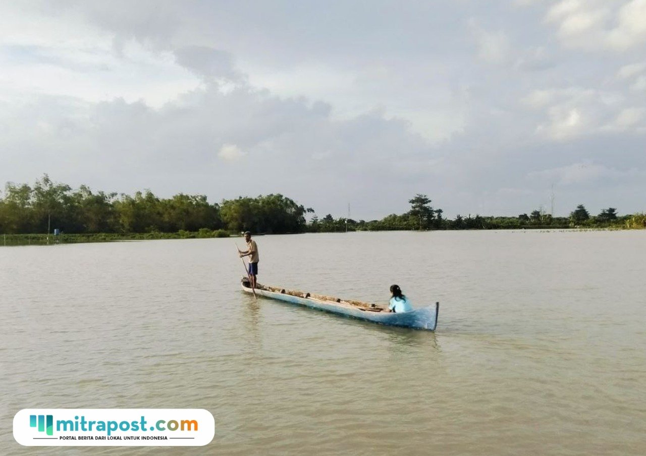 Foto : Rukin seorang petani Desa Banjarsari, Kecamatan Gabus menaikan perahu melintasi lahan sawahnya. (Sumber. Mitrapost.com/ Ilham)