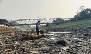 Foto : Nelayan sungai naik perahu saat sungai mengering. (Sumber. Mitrapost.com/ Ilham)
