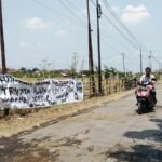 Foto : Jalan di Bumirejo Kecamatan Margorejo dipasangi spanduk bernada kritik. (Sumber. Mitrapost.com/ Ilham) Foto : Jalan di Bumirejo Kecamatan Margorejo dipasangi spanduk bernada kritik. (Sumber. Mitrapost.com/ Ilham)