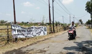 Foto : Jalan di Bumirejo Kecamatan Margorejo dipasangi spanduk bernada kritik. (Sumber. Mitrapost.com/ Ilham)