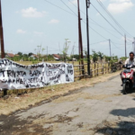 pati Foto : Jalan Rusak Dipasangi Spanduk di Desa Bumirejo Kecamatan Margorejo. (Sumber. Mitrapoat.com/ Ilham)